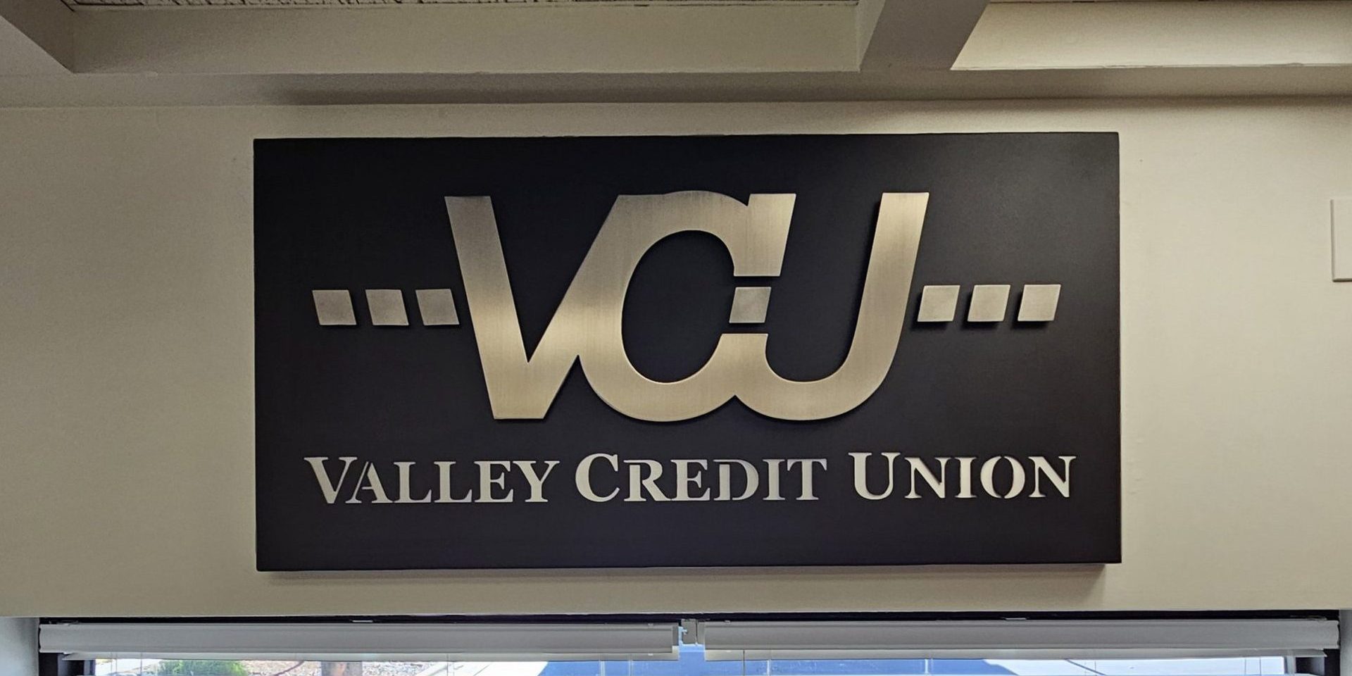 Custom metal sign layered and stencil cut for Valley Credit Union drive-up window wall.