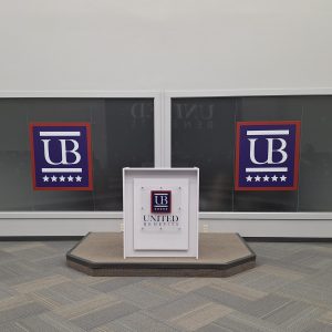 Printed acrylic logo sign for podium and logo decals for glass to brand throughout the company at United Benefits.
